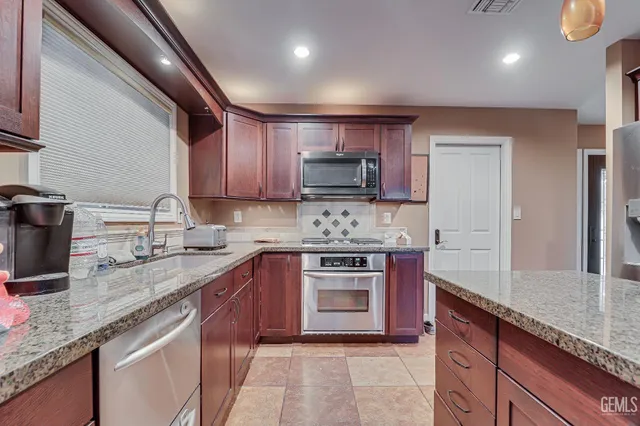 a kitchen with stainless steel appliances granite countertop a sink stove and refrigerator