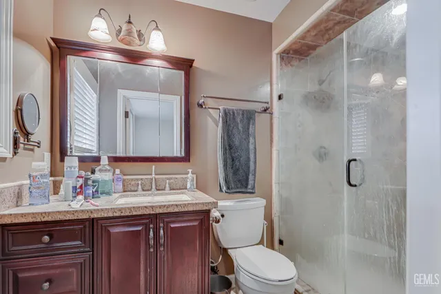 a bathroom with a sink vanity granite toilet and shower