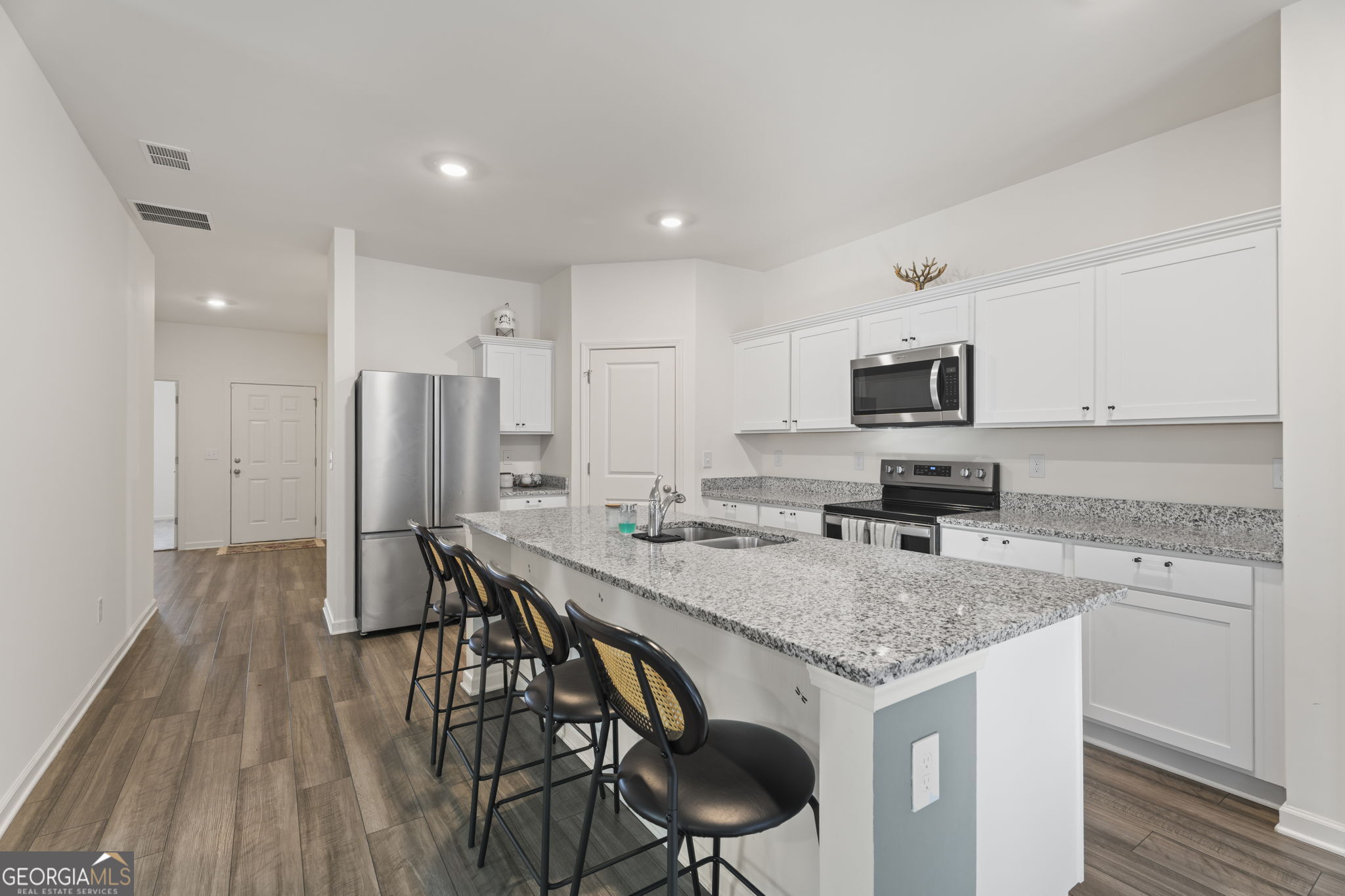 119 Bantry Way Locust Grove, GA 30248 - Photo 7 of 34 a kitchen with stainless steel appliances granite countertop a kitchen island hardwood floor sink stove and microwave
