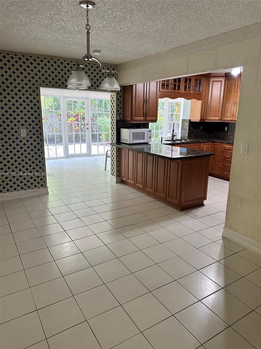9110 Southwest 9th Terrace, Unit 9110 Miami, FL 33174 - Photo 4 of 17 a kitchen with granite countertop a stove a sink and a microwave