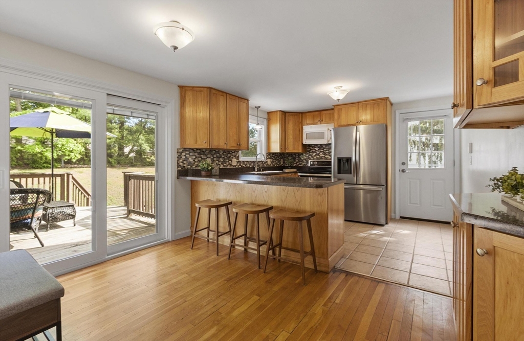 6 Edith Road Hudson, MA 01749 - Photo 5 of 30 a kitchen with granite countertop a refrigerator a stove top oven and a dining table with wooden floor