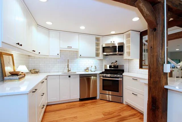 a kitchen with stainless steel appliances a dining table chairs and wooden floor