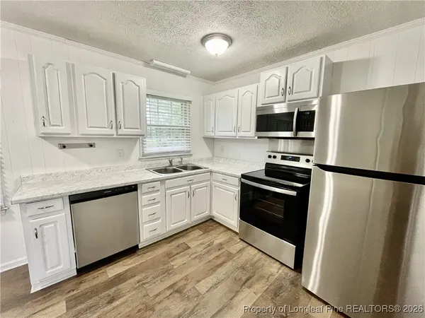 a kitchen with granite countertop a refrigerator stove and microwave