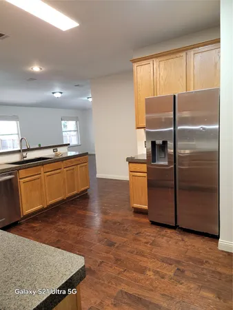 a kitchen with granite countertop a refrigerator a sink a stove and cabinets