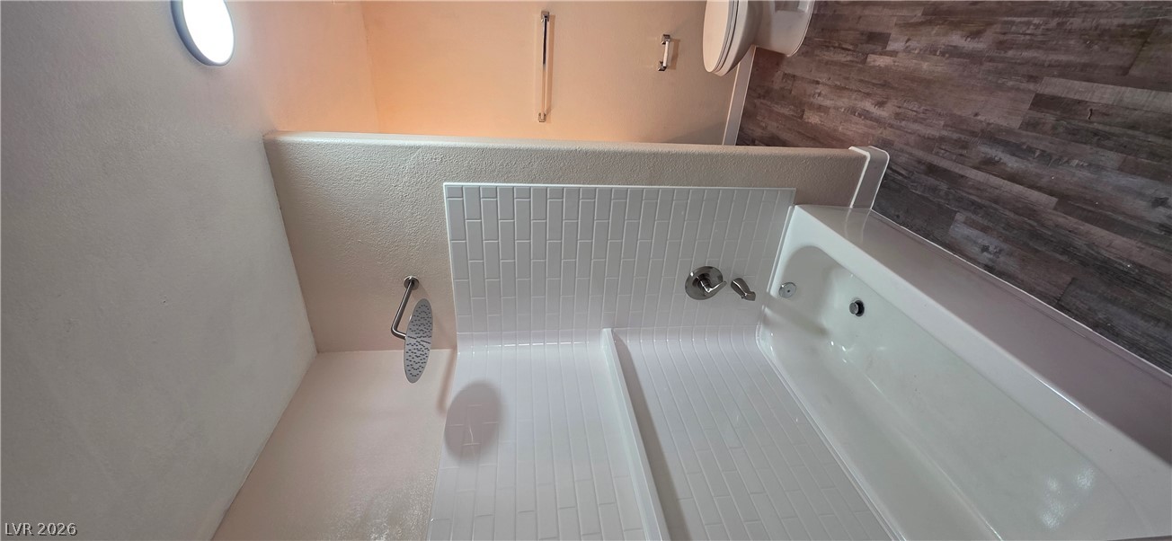 1830 North Pecos Road, Unit 142 Las Vegas, NV 89115 - Photo 18 of 19 A well-appointed bathroom with durable plank flooring, a classic bathtub, and sleek subway tile accents.