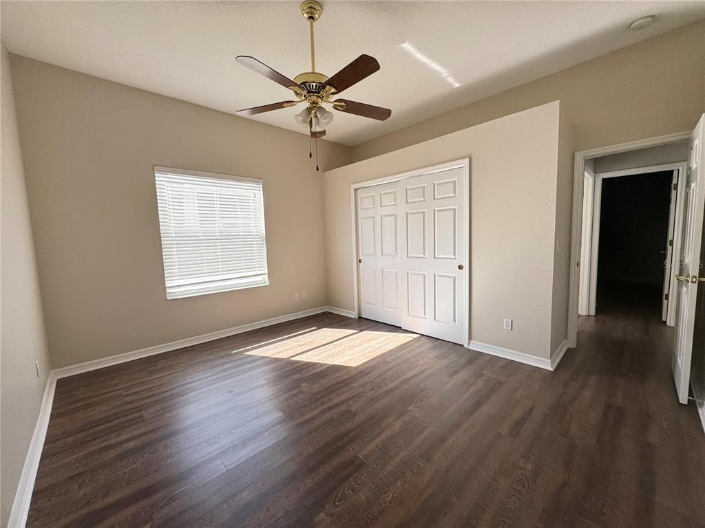 28724 Hanging Moss Loop Wesley Chapel, FL 33543 - Photo 19 of 30 an empty room with wooden floor chandelier fan and windows