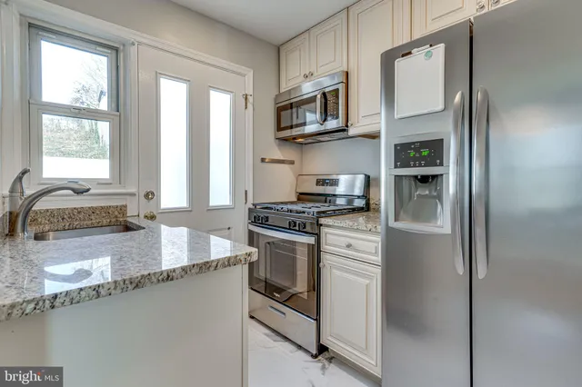 a kitchen with stainless steel appliances granite countertop a refrigerator a stove and a sink