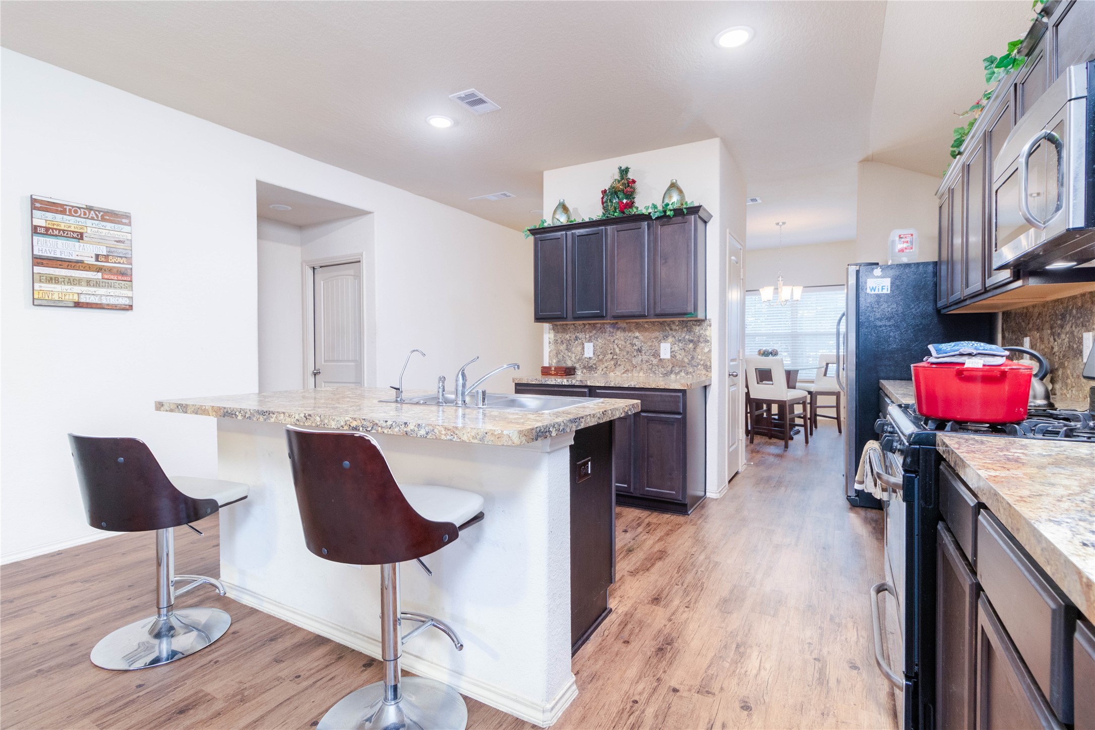 24423 Raindrop Poppy Drive Spring, TX 77373 - Photo 4 of 29 a kitchen with kitchen island granite countertop wooden floors and a view of living room