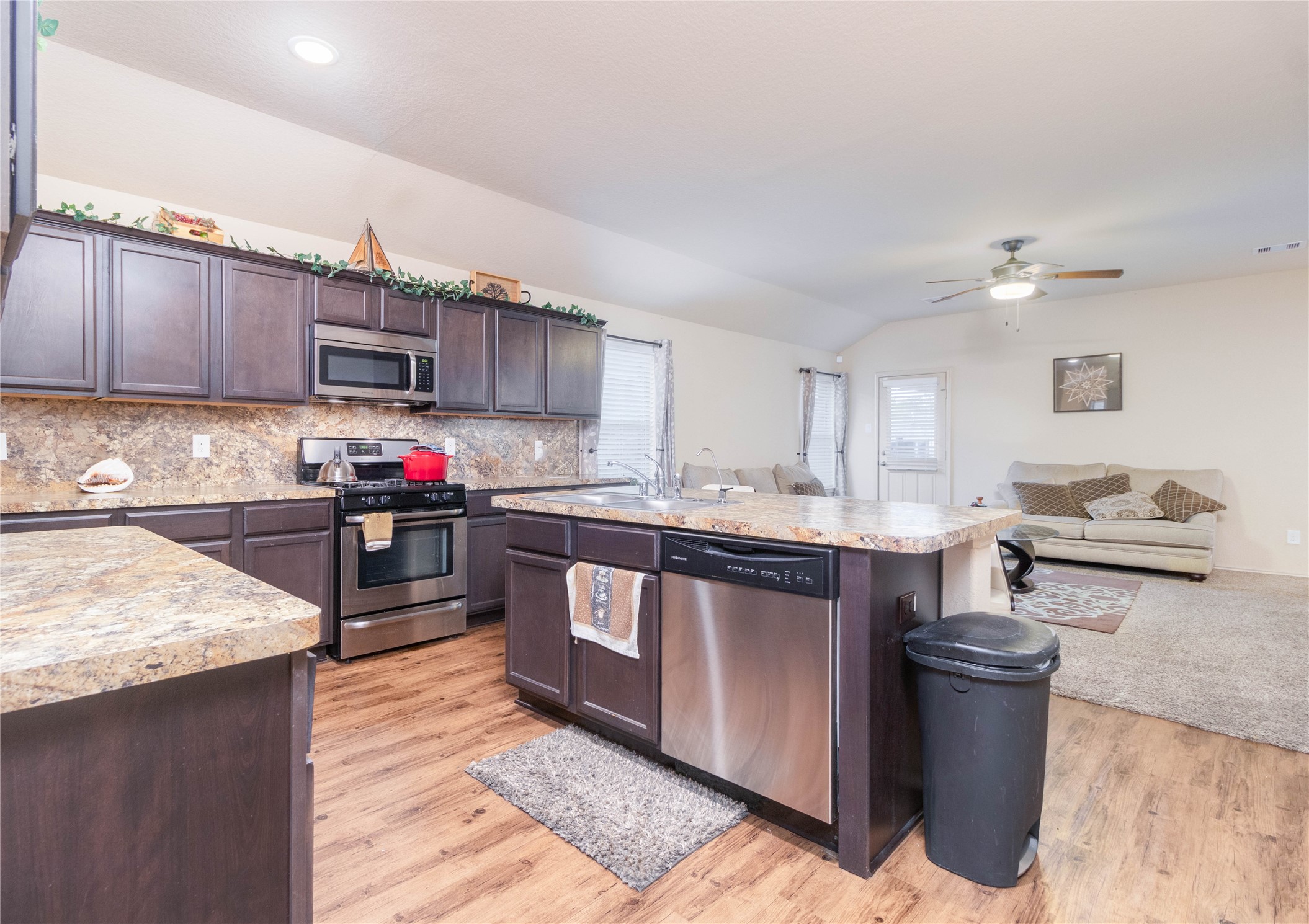 24423 Raindrop Poppy Drive Spring, TX 77373 - Photo 5 of 29 a kitchen with a stove top oven a sink dishwasher and a refrigerator with wooden cabinets