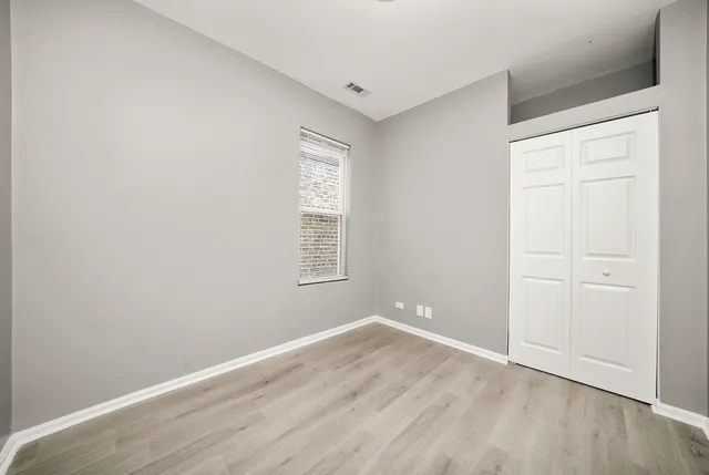 an empty room with wooden floor and window