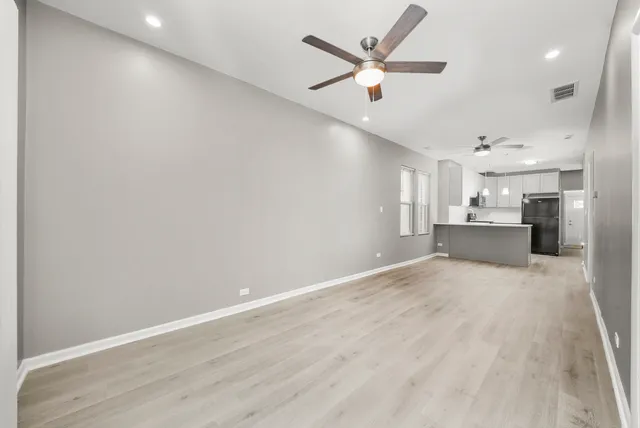 an empty room with a kitchen and a ceiling fan