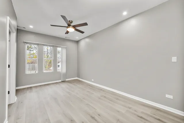 an empty room with wooden floor fan and windows