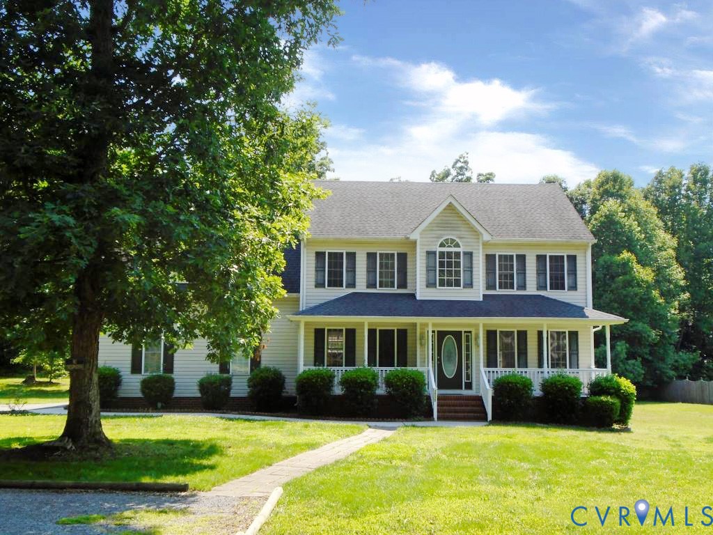 a front view of a house with garden and trees