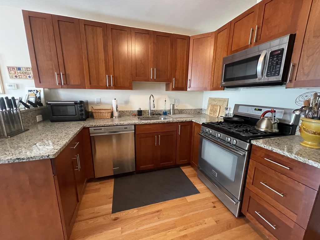 a kitchen with stainless steel appliances granite countertop wooden cabinets a stove top oven a sink and dishwasher