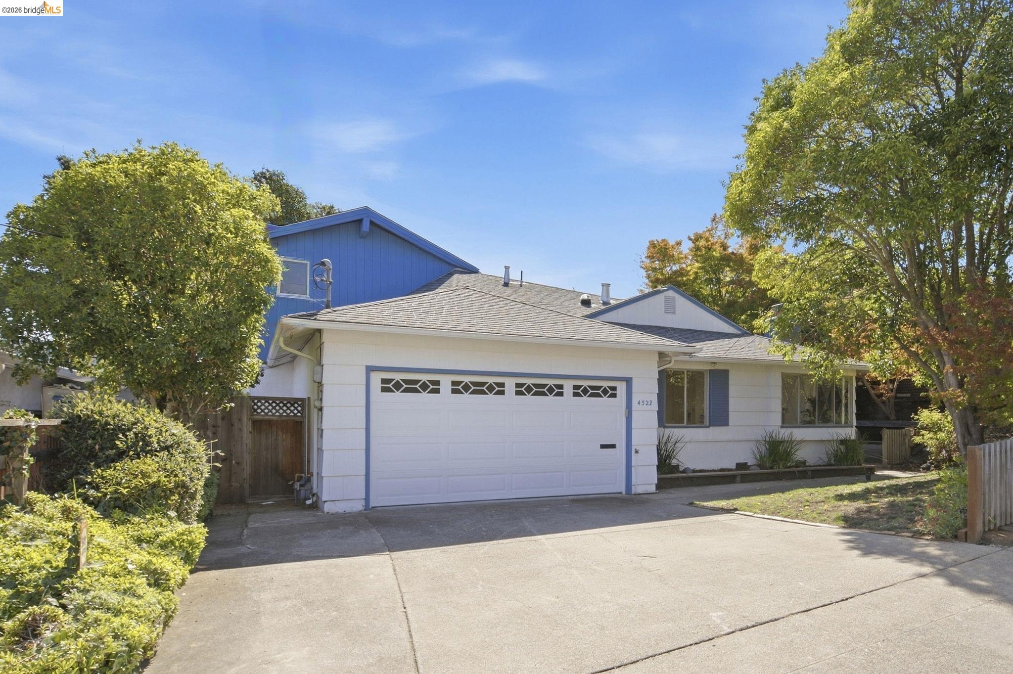 Single-family residence featuring a two-car garage with decorative windows, a concrete driveway, and mature landscaping