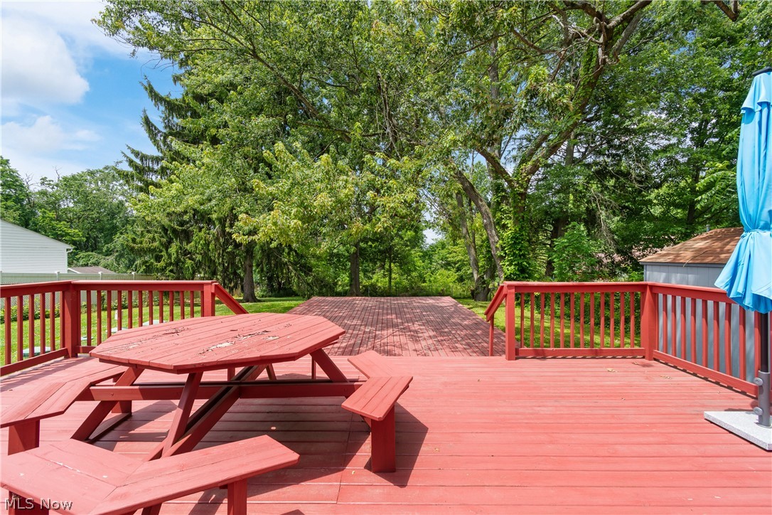 5768 Nolley Road Akron, OH 44319 - Photo 21 of 38 Expansive red-stained wood deck featuring a built-in picnic table, red-stained railings, and mature trees providing a natural backdrop