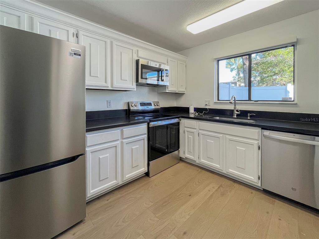4001 South Beneva Road, Unit 416 Sarasota, FL 34233 - Photo 5 of 19 a kitchen with granite countertop white cabinets white appliances a sink and a window