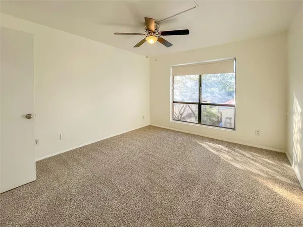 an empty room with windows and ceiling fan