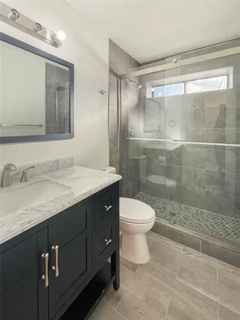 a bathroom with a granite countertop sink toilet and shower