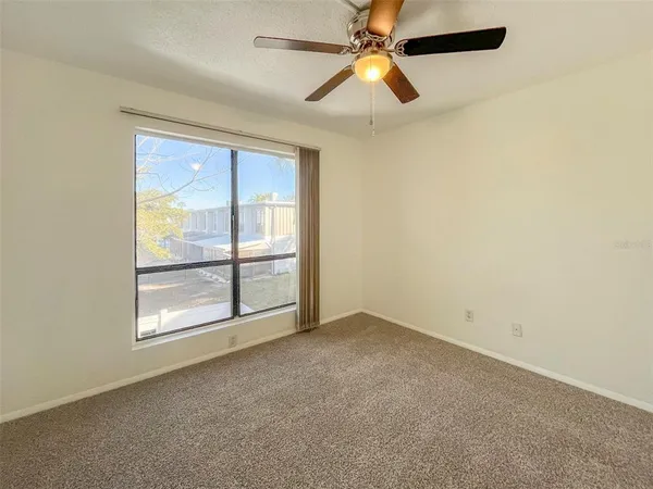 an empty room with windows and fan