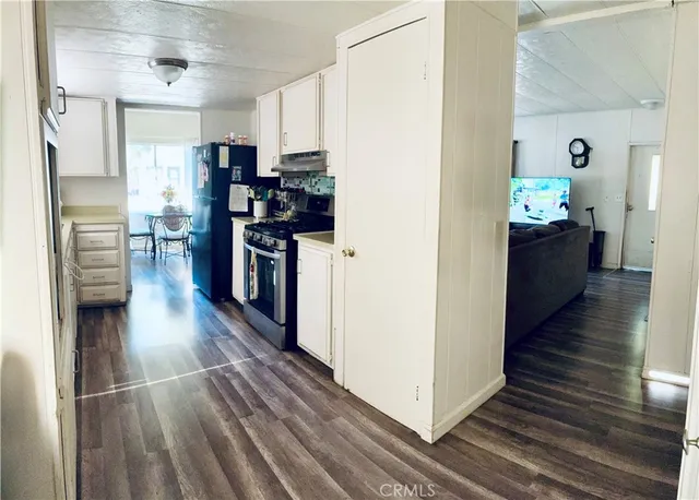 a kitchen view with wooden floor stainless steel appliances and cabinets