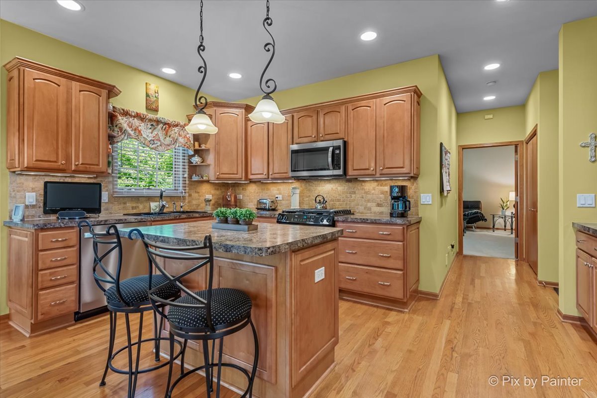 3720 Cypress Drive Spring Grove, IL 60071 - Photo 17 of 55 a kitchen with stainless steel appliances granite countertop a stove top oven a refrigerator a sink and chairs