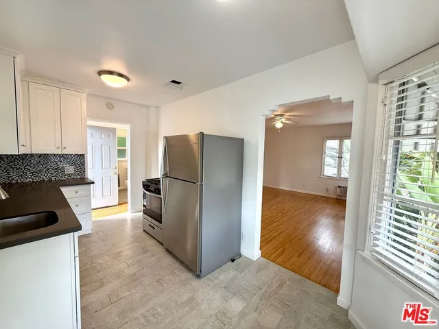 a view of a kitchen with a refrigerator a stove top oven and cabinets