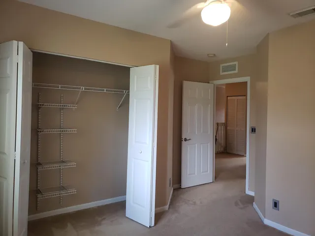a view of an empty room with closet and a bathroom
