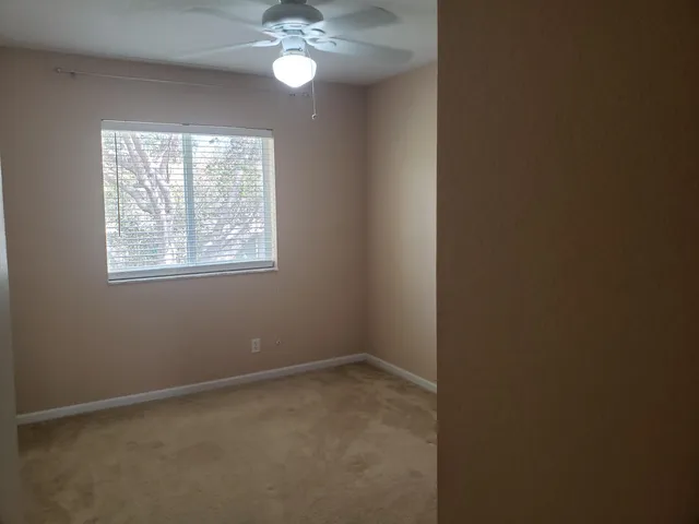 an empty room with a chandelier fan and windows