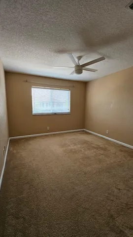 en empty room with windows and ceiling fan