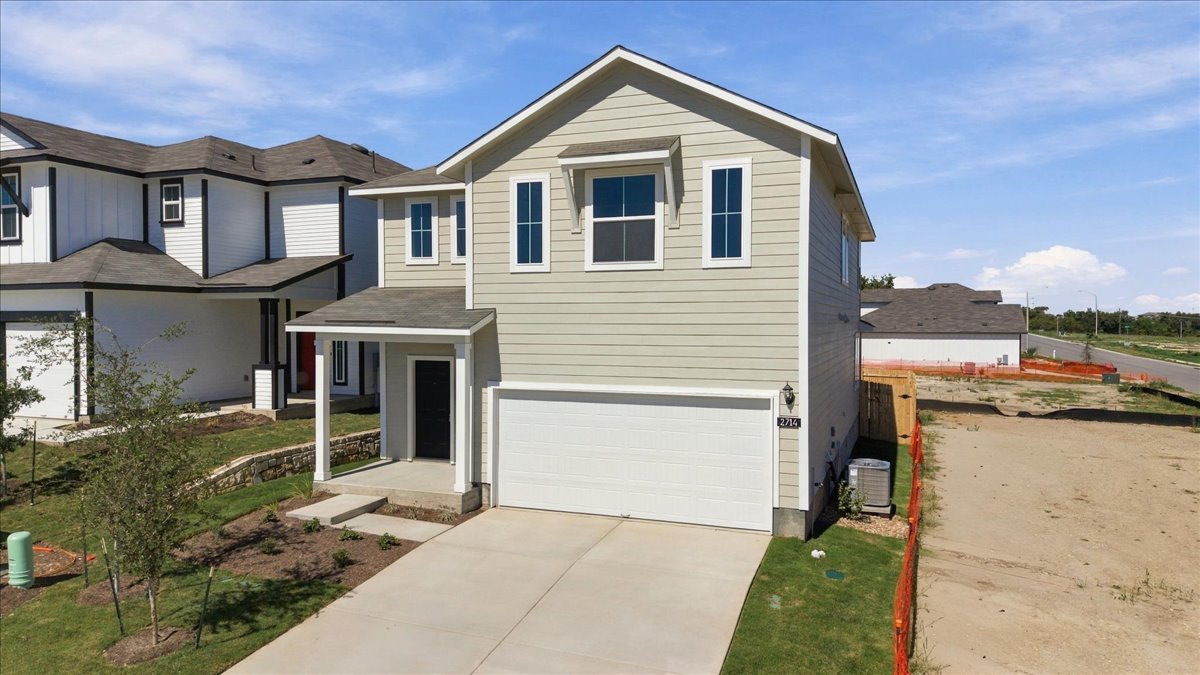 A classic two-story exterior showcases horizontal siding and a spacious concrete driveway leading to the garage.
