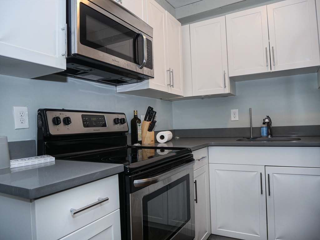 45 Carlton Street, Unit 9 Brookline, MA 02446 - Photo 3 of 8 a kitchen with stainless steel appliances granite countertop white cabinets stove a sink and dishwasher