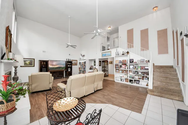 a living room with furniture a fireplace kitchen view and a chandelier