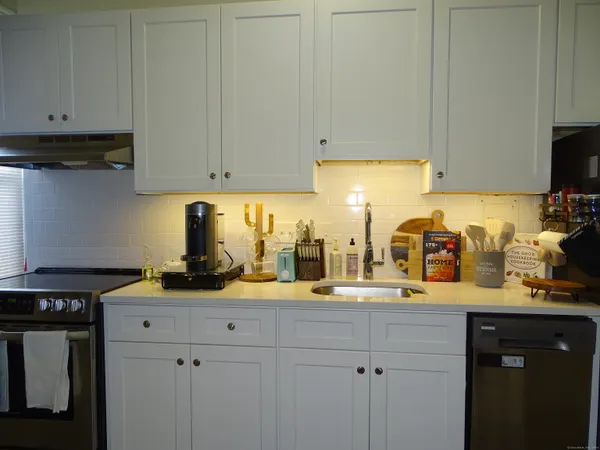 a kitchen with granite countertop a sink a stove and white cabinets