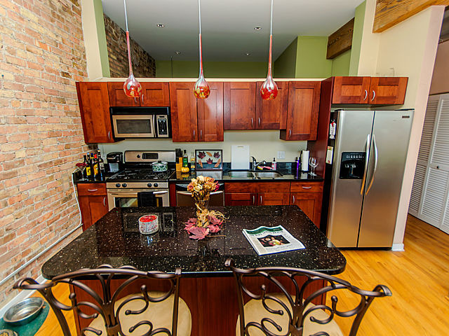 1344 West Madison Street, Unit 303 Chicago, IL 60607 - Photo 9 of 20 a kitchen with stainless steel appliances granite countertop a stove top oven a sink and a microwave