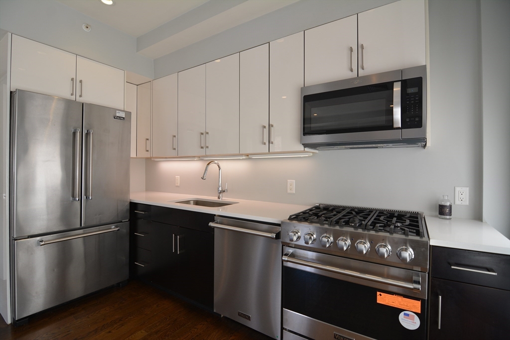 a kitchen with stainless steel appliances a stove a microwave and a hard wood floors