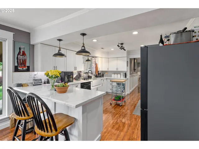 a kitchen with stainless steel appliances kitchen island granite countertop a table chairs and a refrigerator