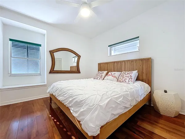 a large bed sitting in a bedroom next to a window and a wooden floor