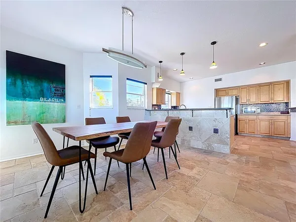 a view of a dining room and livingroom with furniture wooden floor a rug a fireplace and a chandelier