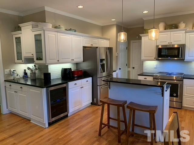 a kitchen with stainless steel appliances granite countertop a stove a sink dishwasher a refrigerator white cabinets and wooden floor