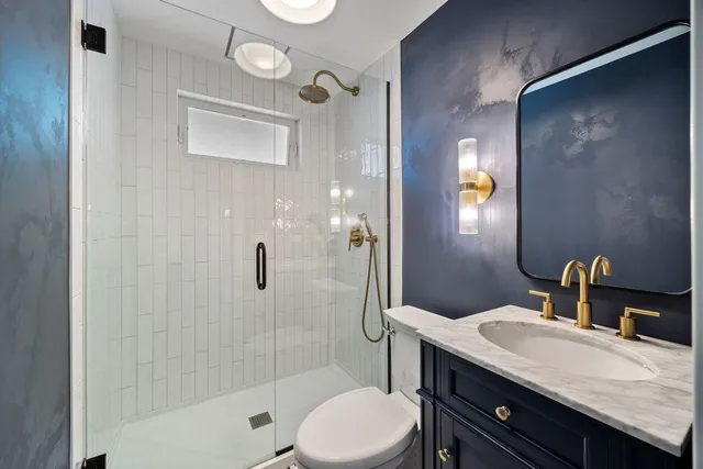 a bathroom with a granite countertop sink toilet and shower