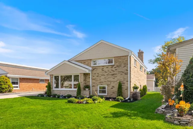 a front view of a house with a garden and trees
