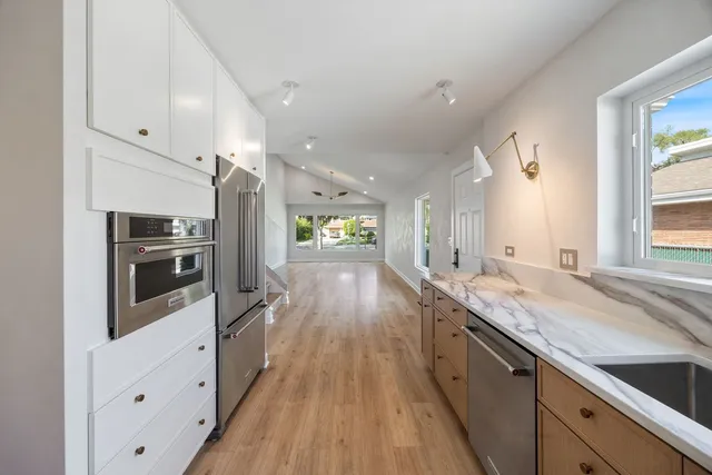 a large kitchen with stainless steel appliances a large counter top a stove and a refrigerator