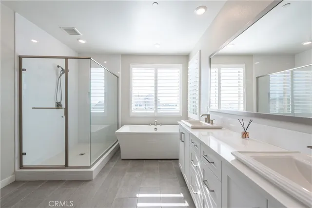 a spacious bathroom with a double vanity sink large mirror and a bathtub