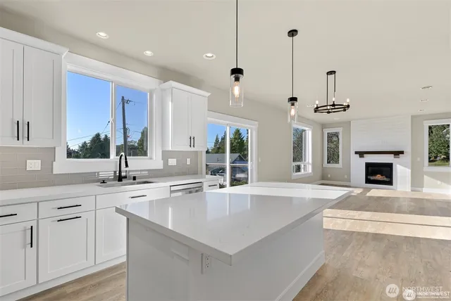 a large kitchen with kitchen island a large counter top a sink stainless steel appliances and cabinets