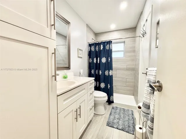 a bathroom with a granite countertop sink a toilet a mirror and shower