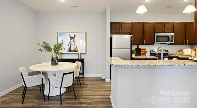 a kitchen with stainless steel appliances granite countertop a refrigerator a stove a sink dishwasher and microwave with wooden floor