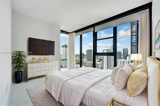 a bedroom with a bed flat screen tv and a large window