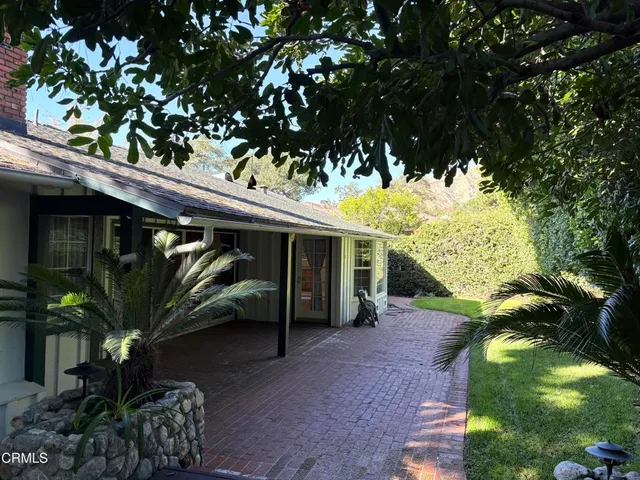 a view of a porch with potted plants and large tree
