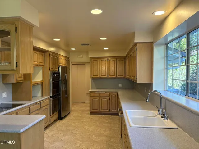a large hall with stainless steel appliances granite countertop a sink and a refrigerator